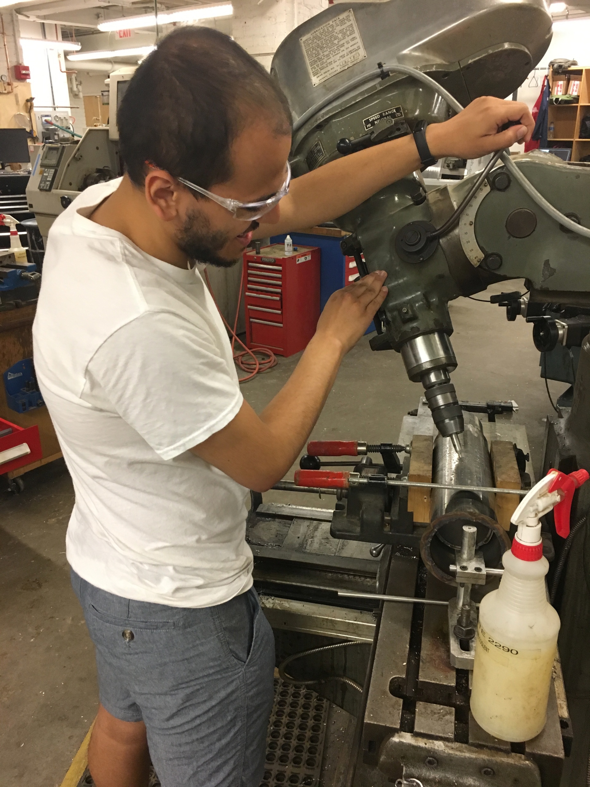 Islam is a member of a small team designing an efficient way to create energy from the combustion of human waste. Pictured here, he is using a compound angle setup on the Bridgeport mill to drill angled holes for air circulation.